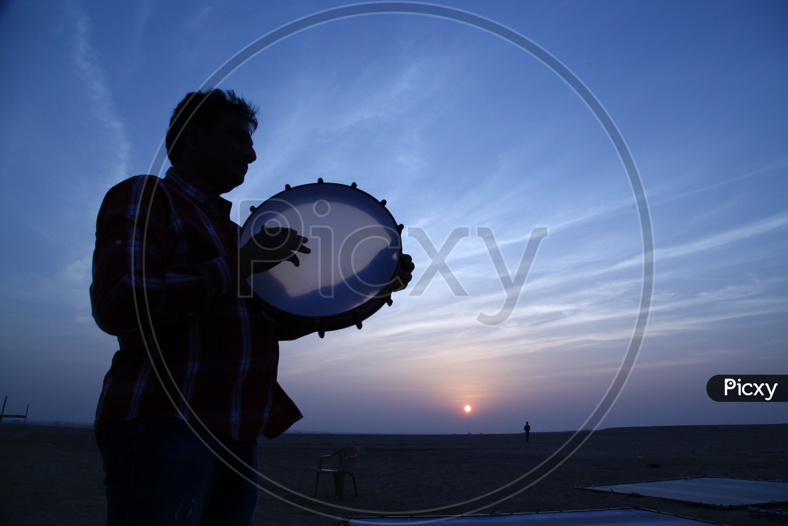 Silhouette of a man playing kanjira
