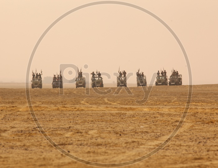 group of people with guns on the vehicles in a desert, bandits