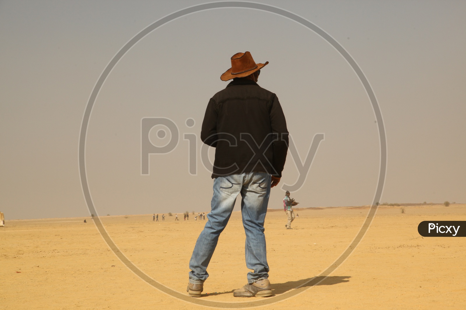A person with cowboy hat standing in the desert