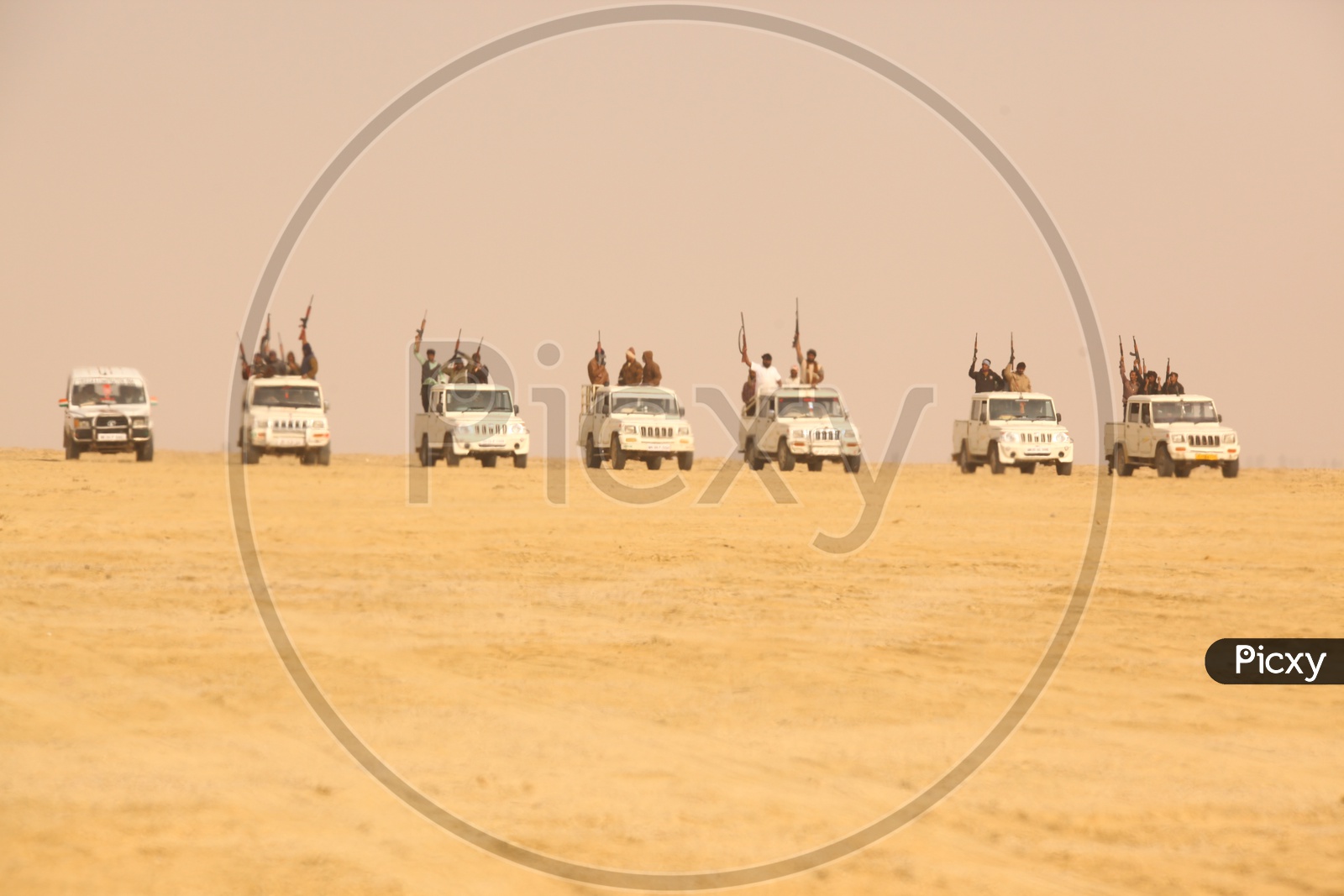 group of vehicles and people with guns in the desert