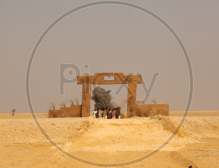 people standing at the arch like entrance in a desert