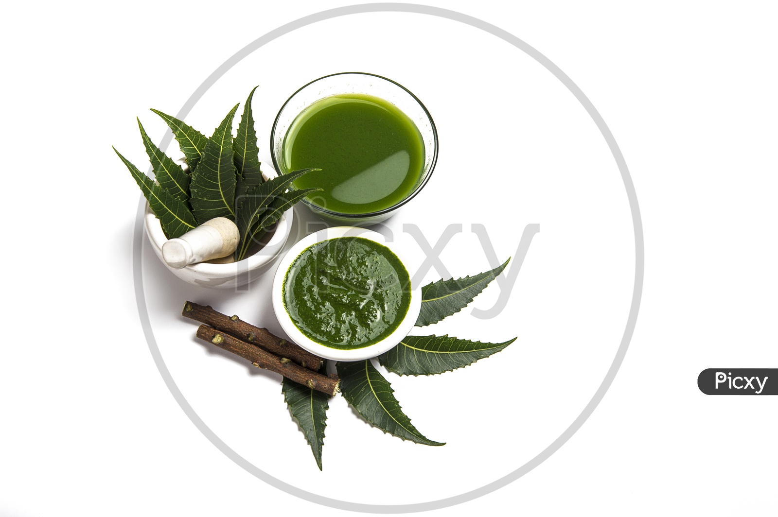Medicinal Neem leaves in mortar and pestle with neem paste, juice and twigs on white background