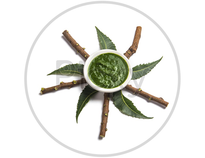 Medicinal Neem leaves with paste in bowl and twigs on white background