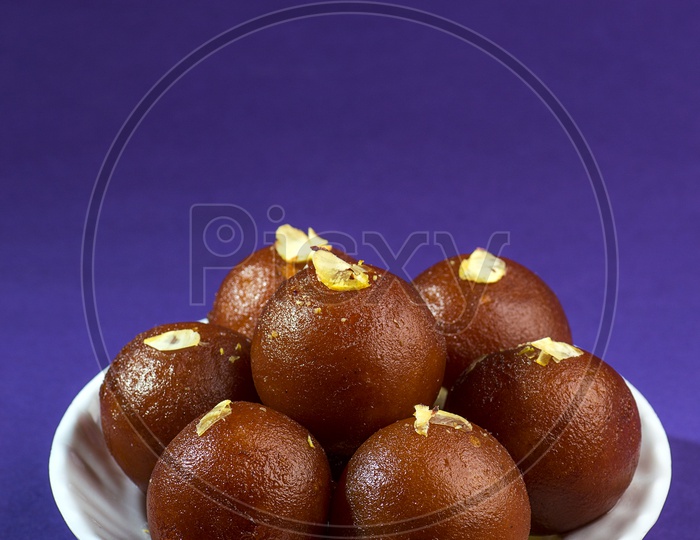Indian Dessert or Sweet Dish Gulab Jamun topped with Pistachio in Plate