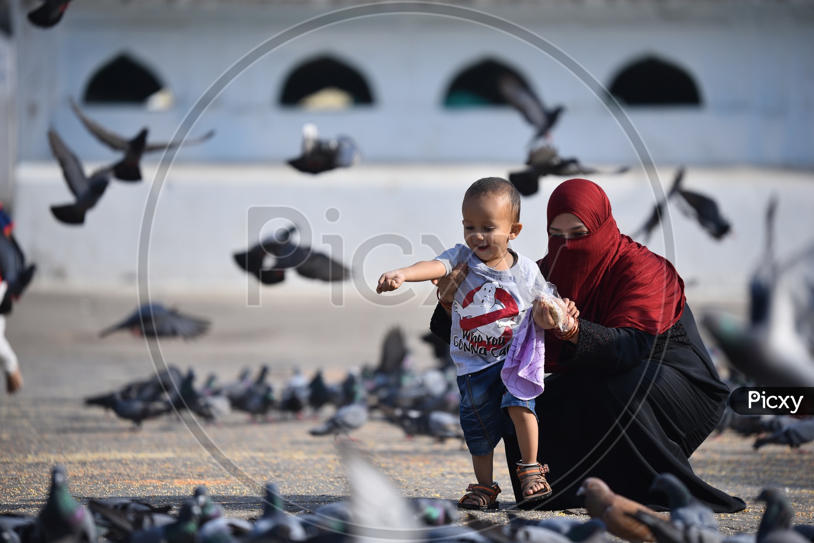 A smiling mother and child try to feed pigeons