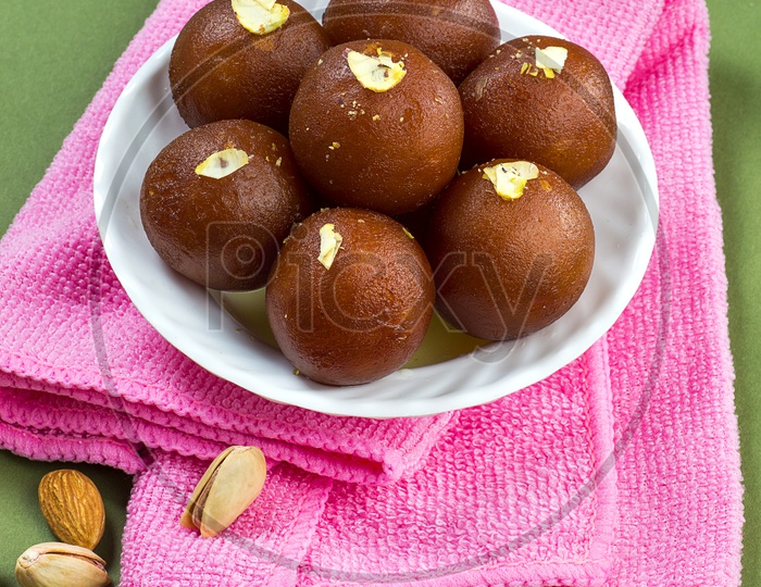 Indian Dessert or Sweet Dish Gulab Jamun topped with Pistachio in Plate with Napkin