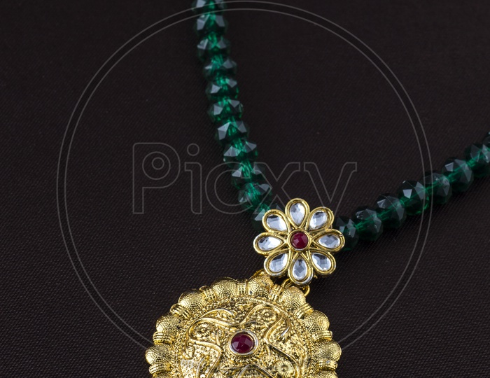 Round shaped gold locket of an emerald beaded chain