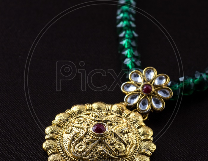 Round shaped gold locket of an emerald beaded chain