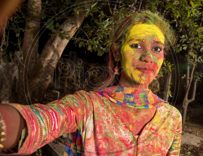 Young Indian Girl Taking Selfies with Colors on Face On Smart Phone