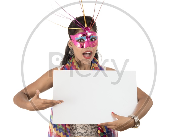 An Young Indian Girl Wearing Carnival Mask and Holding White Board  and Showing the Space