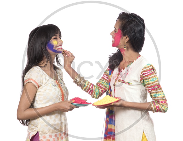 Young Indian Girls Holding Holi Color Powder Plates and Celebrating Holi by Painting Color Each Other
