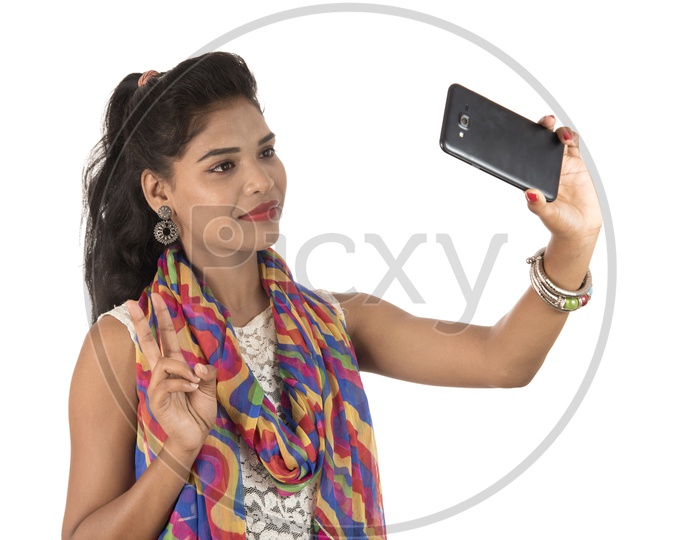 An Young Indian Girl Taking Selfie With Smart Phone And Showing Victory Symbol
