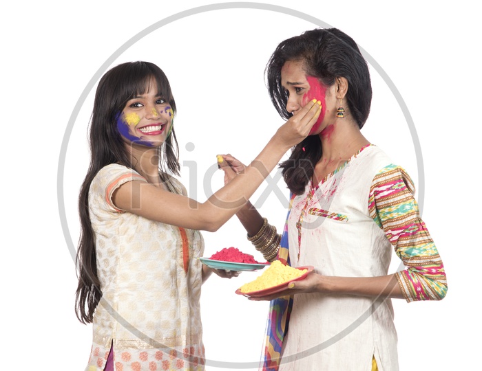 Young Indian Girls Holding Holi Color Powder Plates and Celebrating Holi by Painting Color Each Other