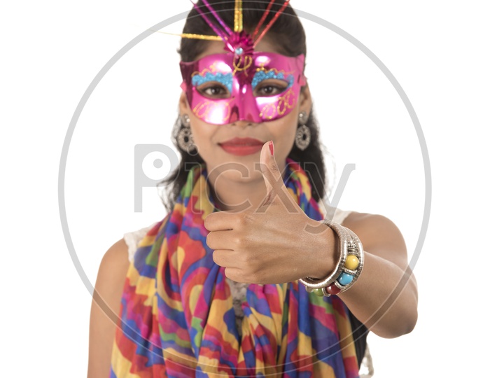 An Young Indian Girl Wearing Carnival Mask and Showing Thumps Up