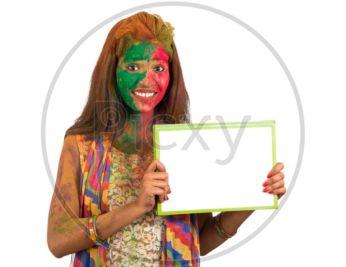 A Happy Young Indian Girl filled in Holi Colors and Showing White Board