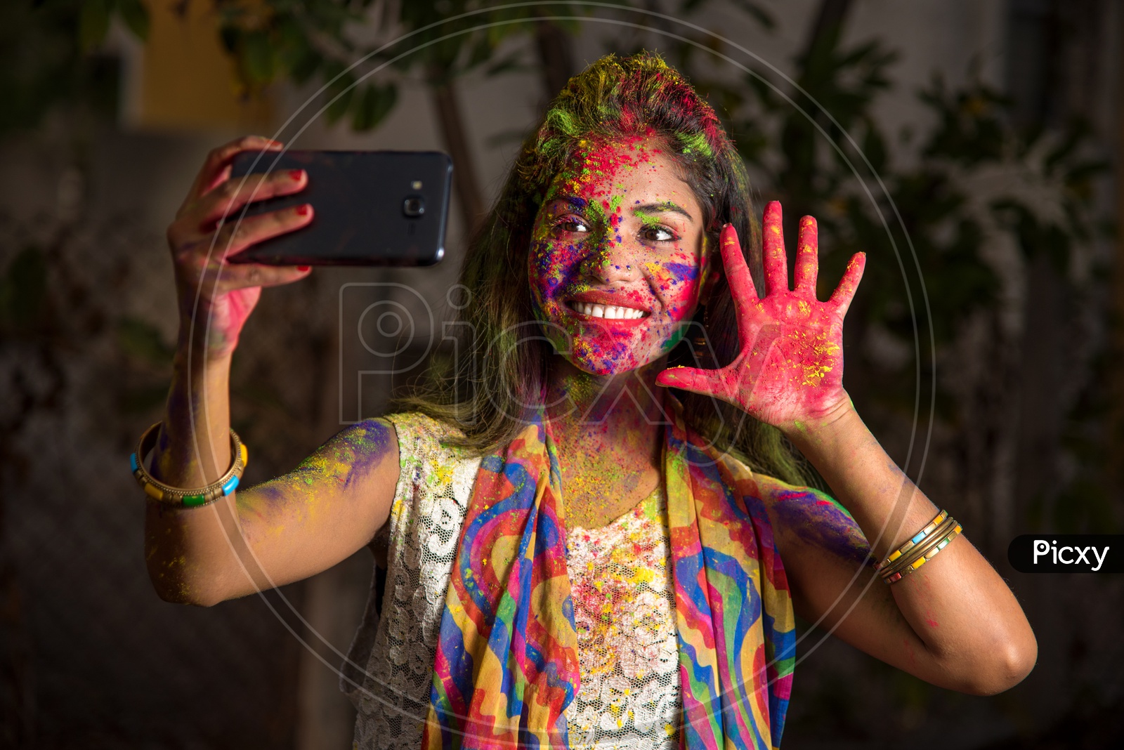 A Happy Young Indian Girl with Holi Colors On Her Taking Selfie With Smart Phone