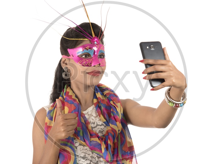 Young Indian Girl Wearing Carnival Mask and Taking Selfie with Smart Phone