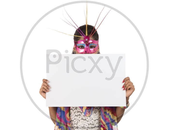 Young Indian Girl Wearing Carnival Mask And Holding White Board or Placard