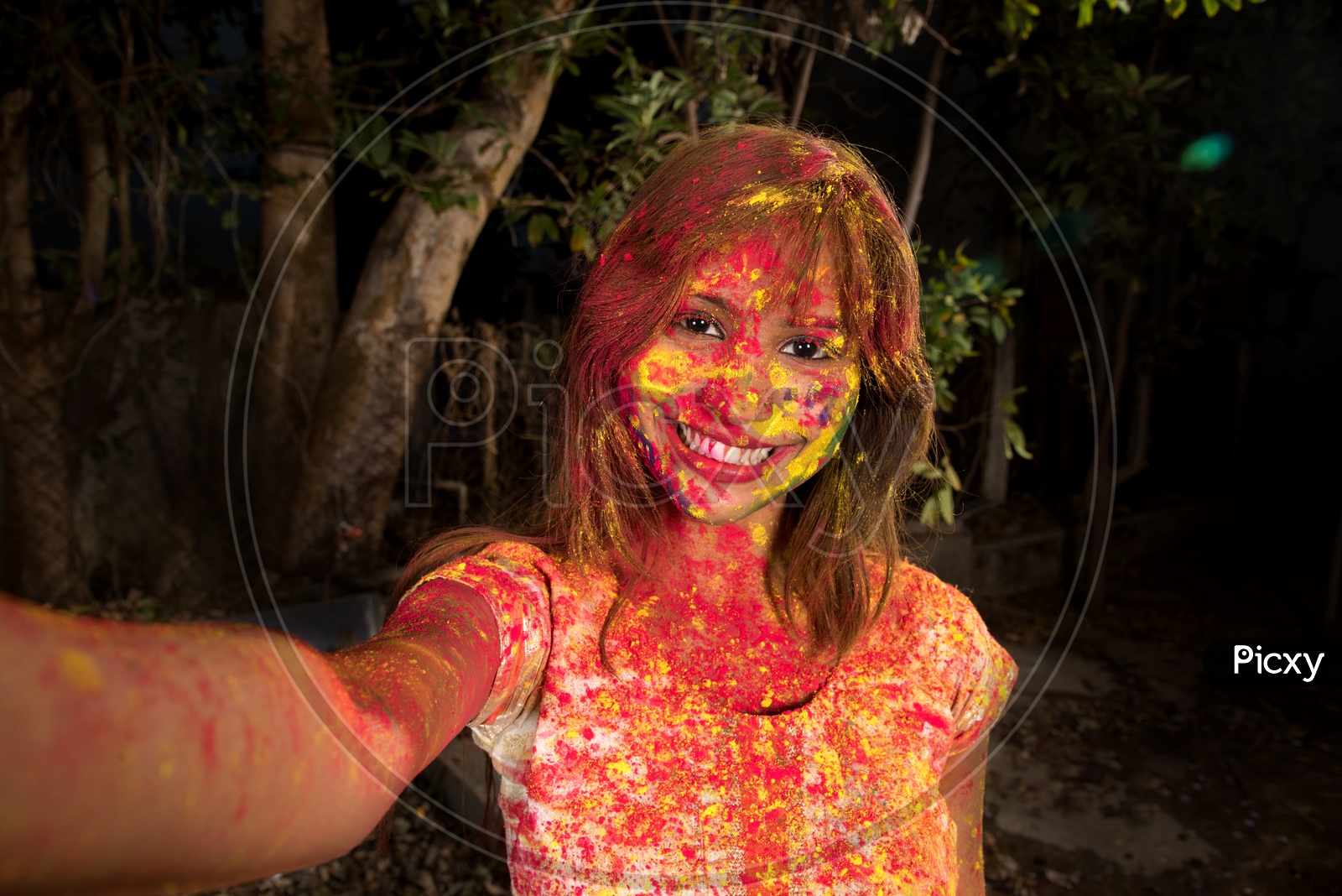 A Happy Young Indian Girl With Holi Colors On  Her and Taking Selfie On Smart Phone