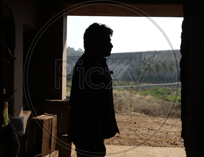 Silhouette of man standing beside the dam