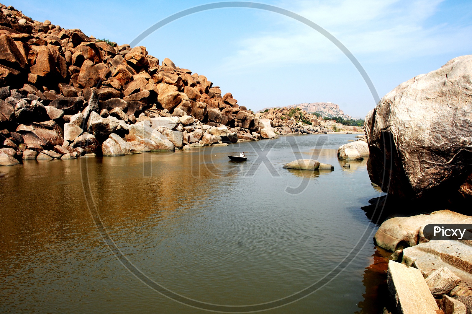 A man in a small boat paddling in Tungabhadra river at Hampi