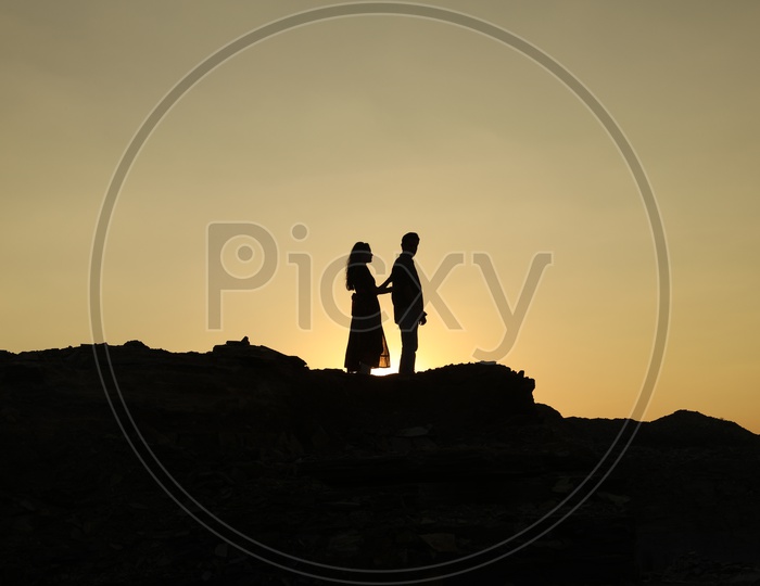Silhouette of a man and a woman on top of the rocky hill
