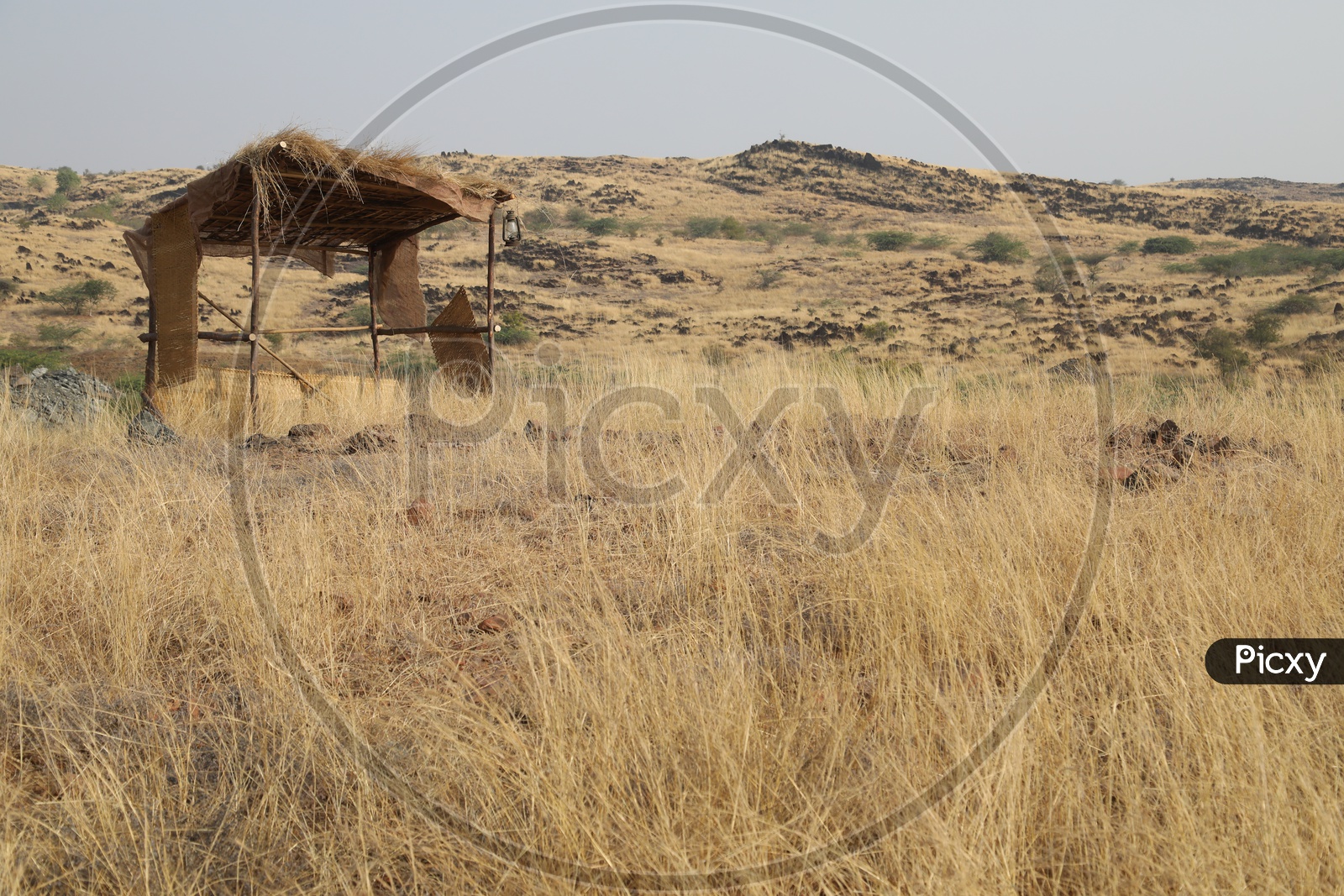 Nipa hut with dry steppe grass in the open area with mountains in the background