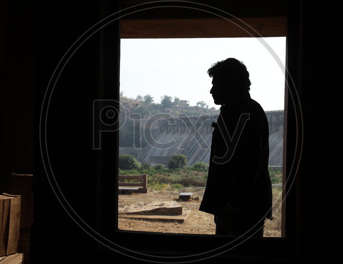 Silhouette of man standing beside the dam