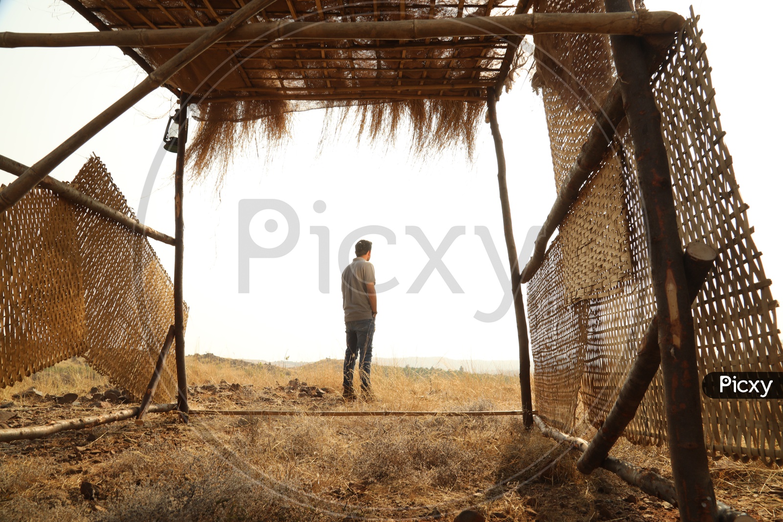 A man seen throught nipa hut with dry steppe grass in the open area