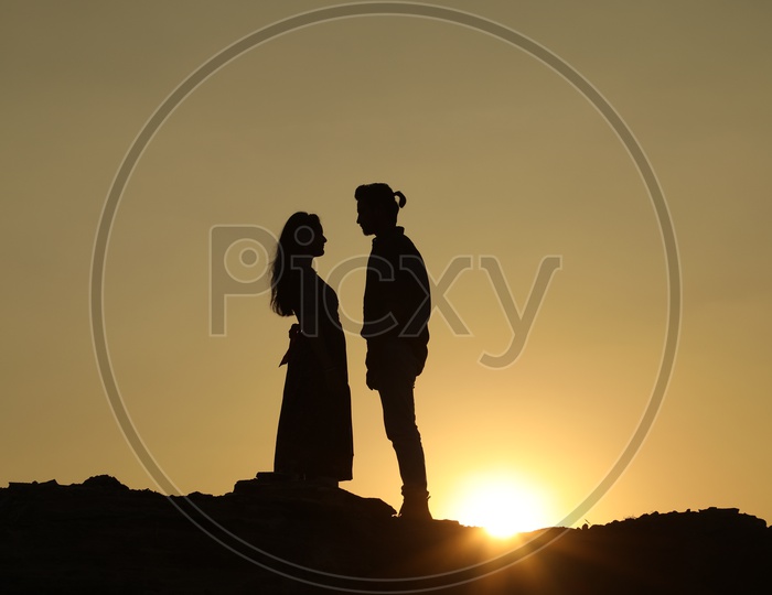 Silhouette of man and woman on top of the rocky hill