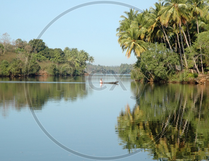 A man in a boat paddling in Mandovi river