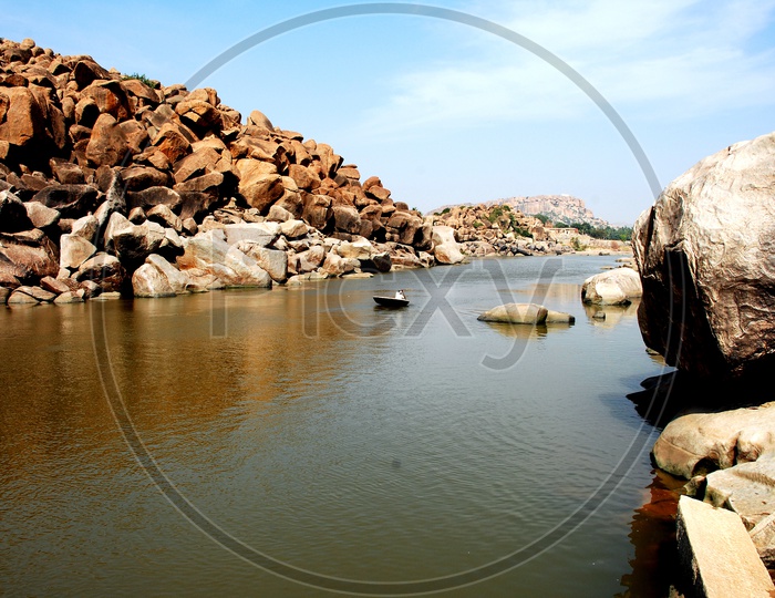 A man in a small boat paddling in Tungabhadra river at Hampi