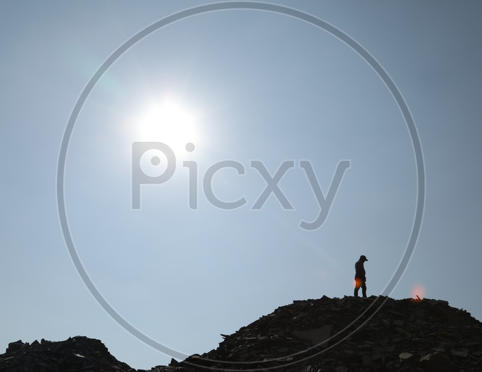 Silhouette of man on the top of the black stone mining area