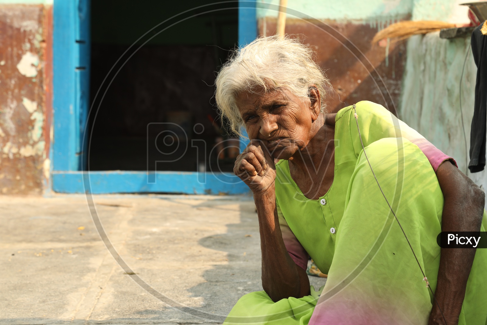 Indian old woman picking something out of her mouth