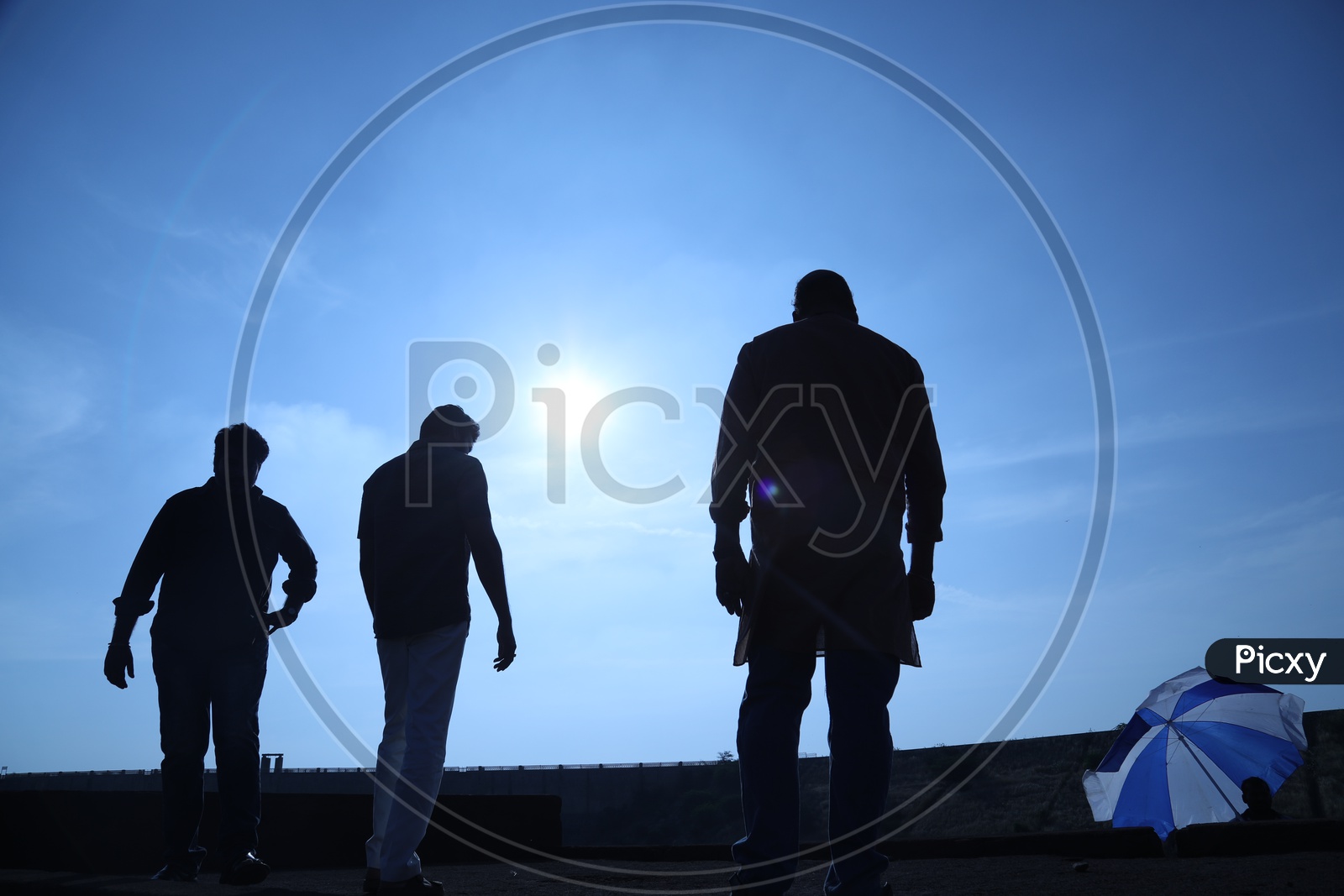 Silhouette of three men walking along the bridge side