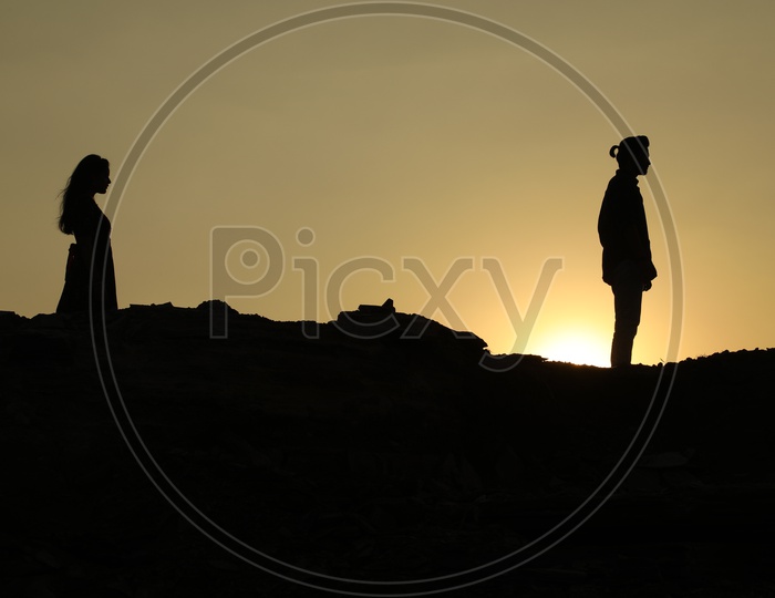 Silhouette of man and woman on the top of the rocky hill