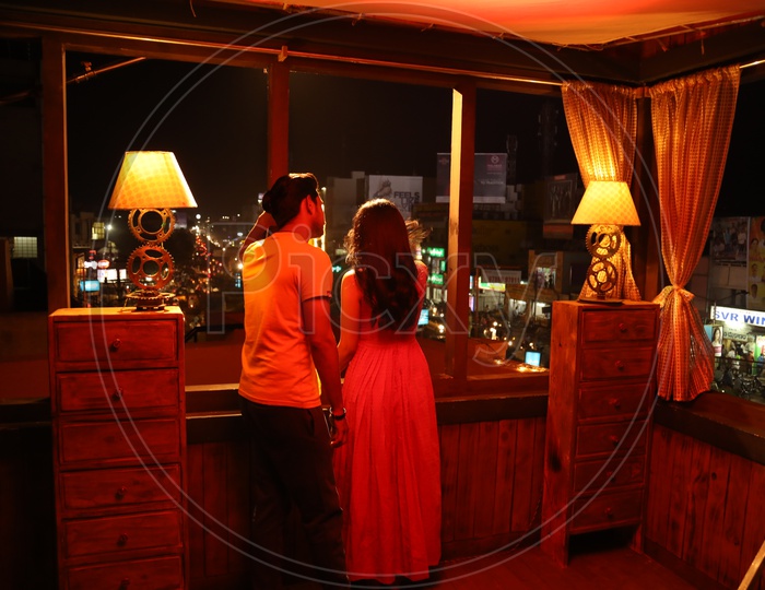 A Couple Standing in a House Balcony With Clock Tower In Background