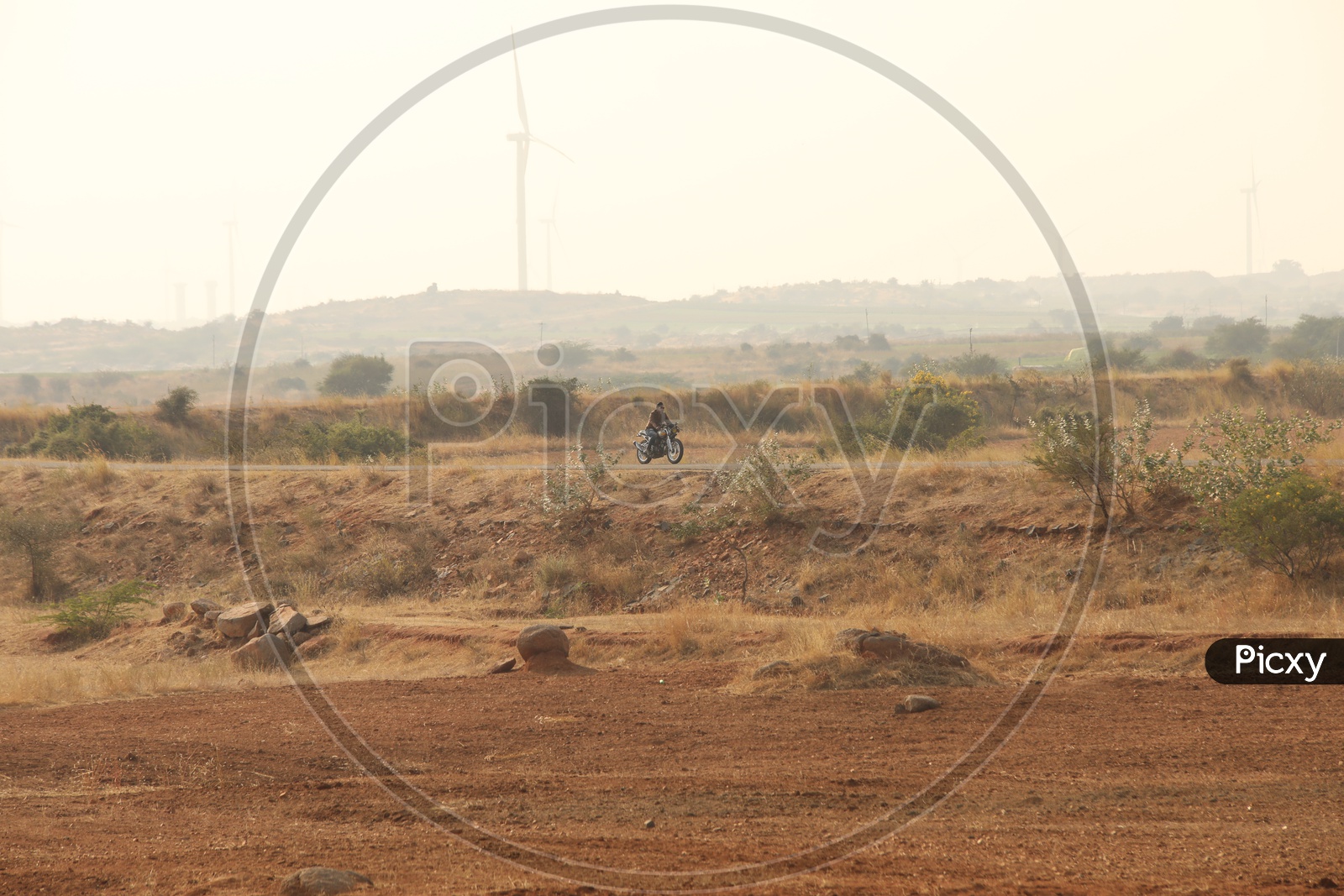Dry steep grass and red mud on the roadside - Biker out of focus