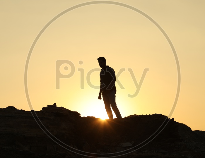 Silhouette of man on the top of the rocky hill