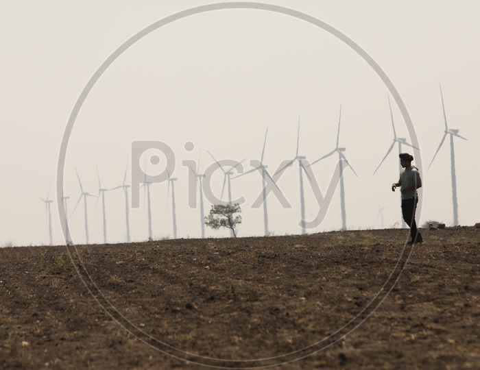 A man Walking Alone On Barren Lands With Wind mills In Background