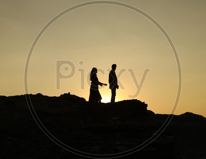 Silhouette of a man and a woman on top of the rocky hill