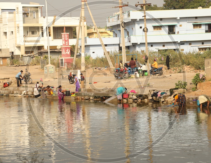 People washing clothes near a pond