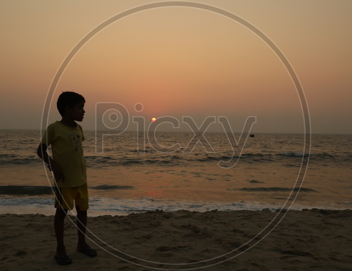 Silhouette Of  a Young Boy On a Beach Watching Sunset