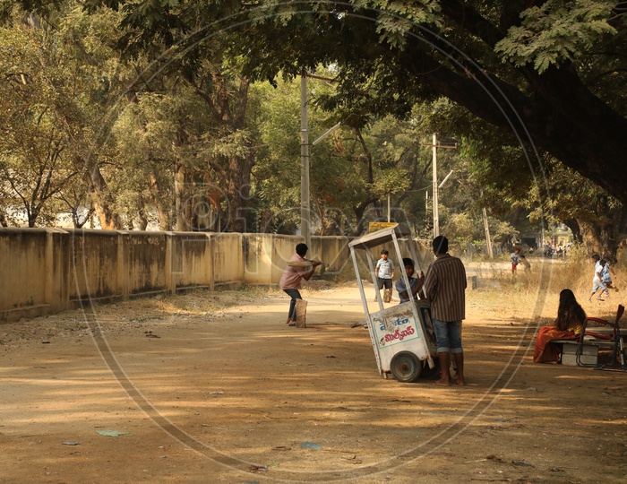 Ice cream vendor is watching children playing cricket on the street