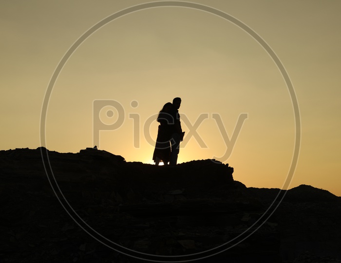 Silhouette of a woman hugging a man on top of the rocky hill