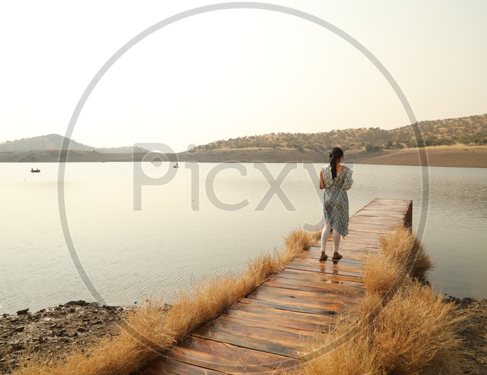 A Young Girl Standing On a Wooden Water bridge