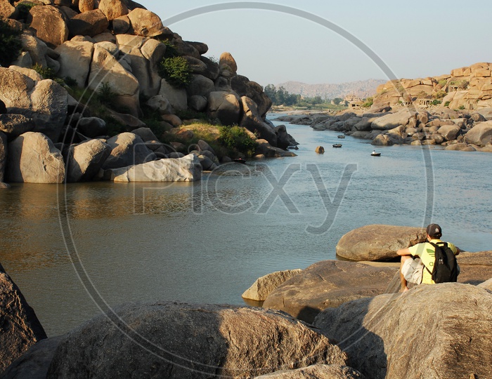 A tourist sitting on rocks in Hampi