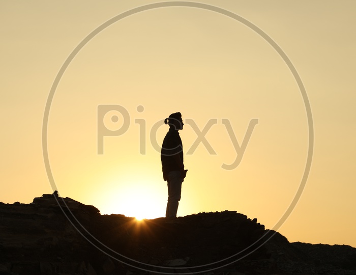 Silhouette of a man on top of the rocky hill