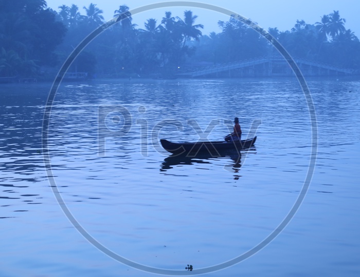 Silhouette Of a Fisher Man In a  Boat In Blue hour  Light