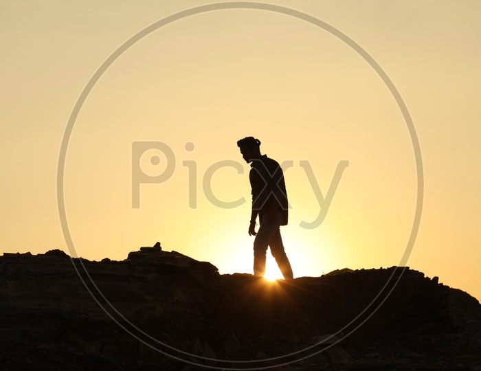 Silhouette of man with a ponytail on the top of the rocky hill